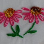 Bloemblaadjes uitgevoerd in madeliefjessteek in twee kleuren.